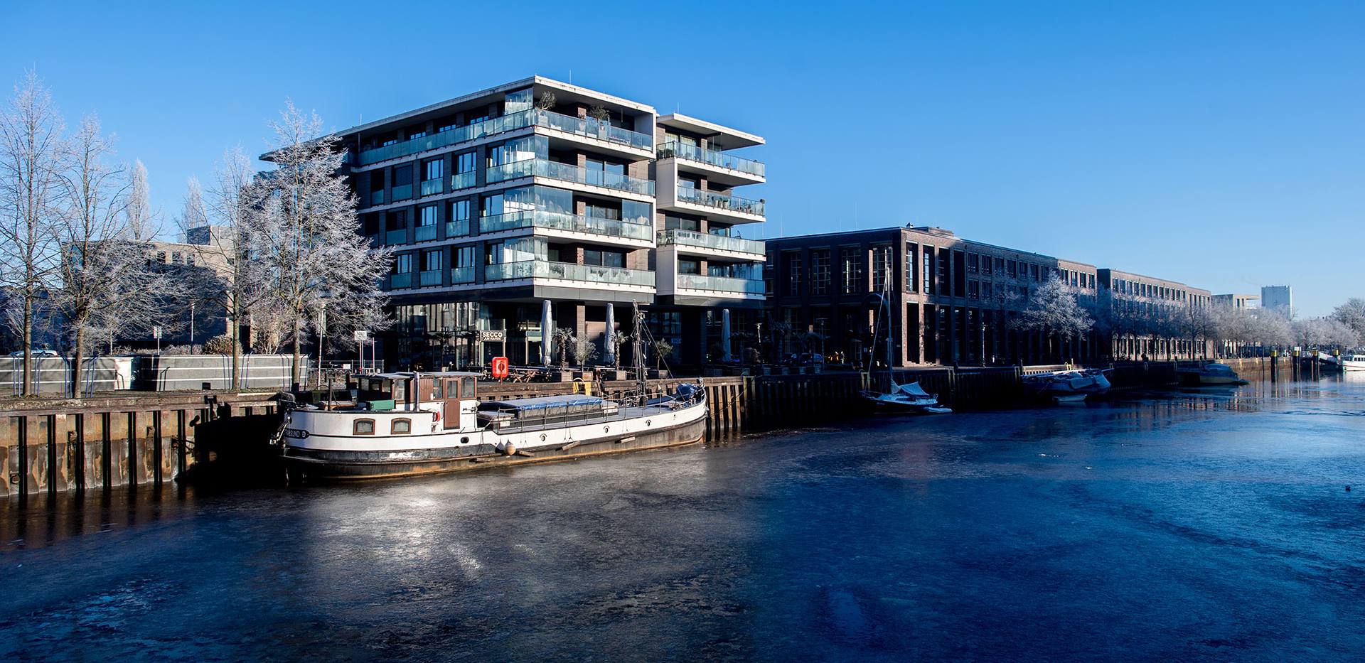 Blick auf den Oldenburger Hafen im Winter mit frostweißen Bäumen und Boot