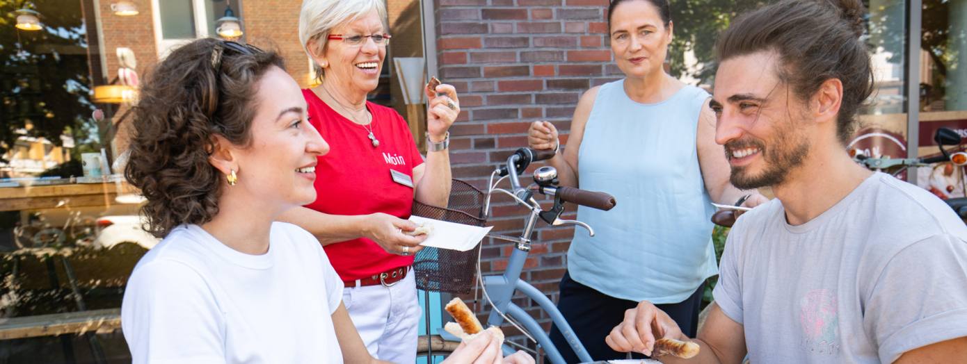 Vier Personen genießen auf einer kulinarischen Stadtführung per Rad einen Snack. 