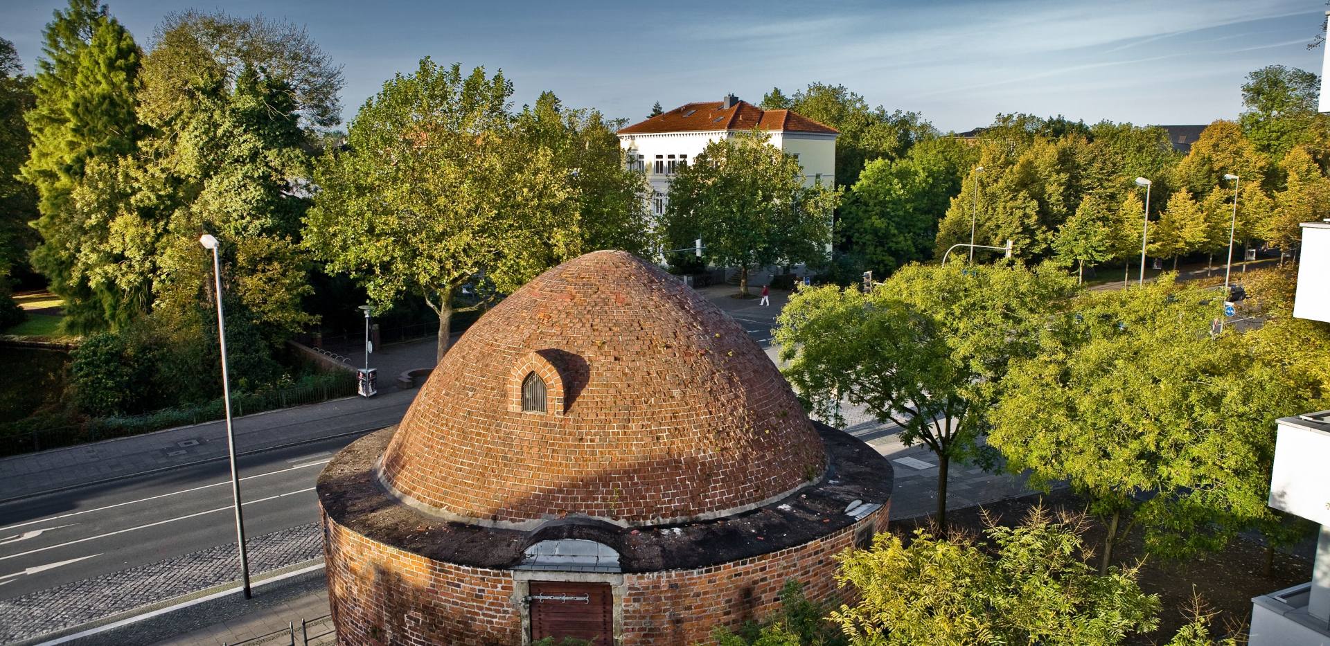 Blick auf den mittelalterlichen Pulverturm mit Stadthaus und Bäumen im Hintergrund.