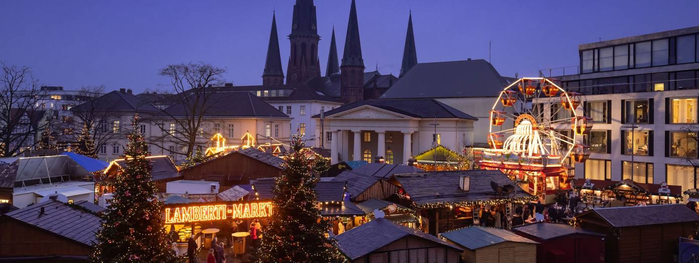 Oldenburger Weihnachtsmarkt auf dem Schlossplatz mit der Schlosswache und der St. Lamberti-Kirche im Hintergrund.