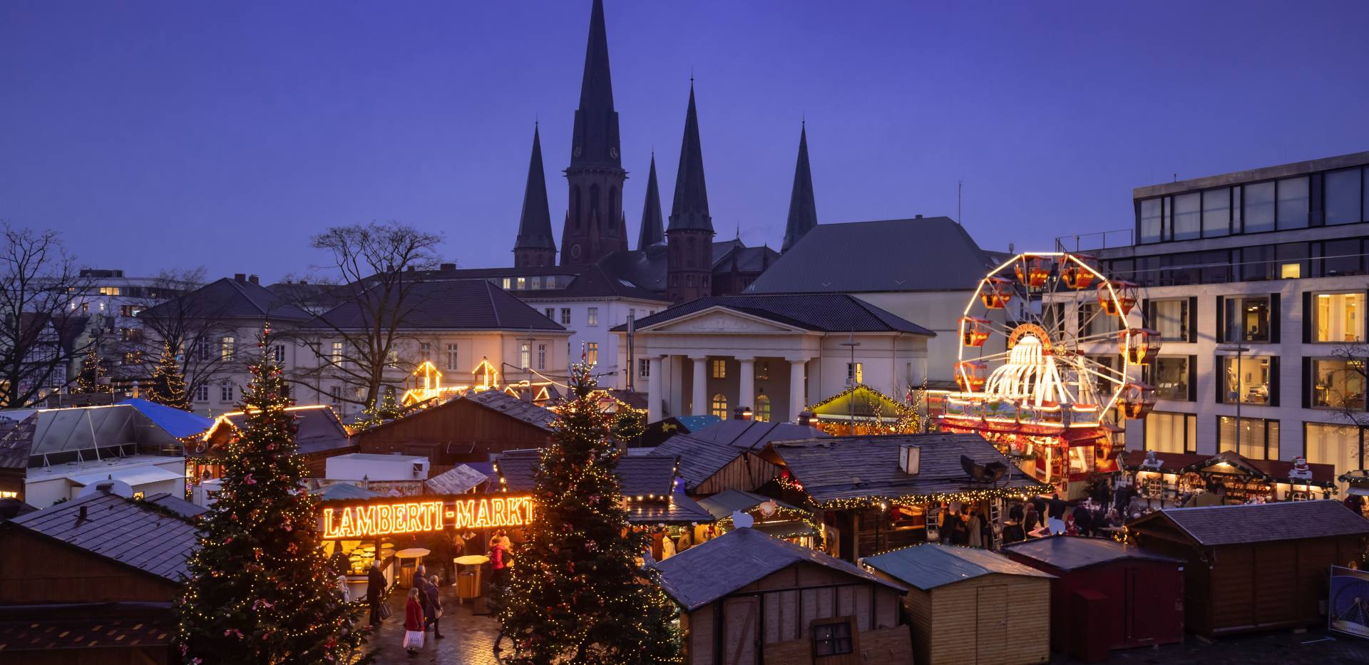 Blick auf den Lamberti-Markt auf dem Schlossplatz mit den Türmen der St. Lamberti-Kirche im Hintergrund. 