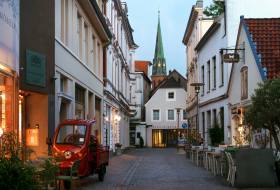 Abendliche Aufnahme der Oldenburger Burgstraße mit Turm der Lamberti-Kirche im Hintergrund