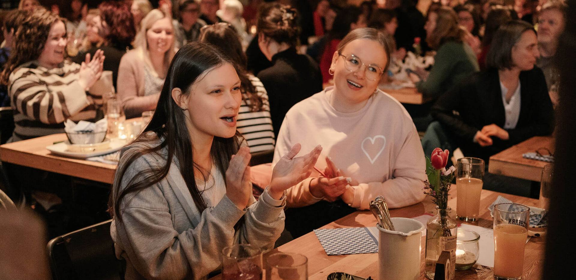 Eine Gruppe von Teilnehmern hebt jubelnd die Arme, als sie eine richtige Antwort beim Pubquiz finden.