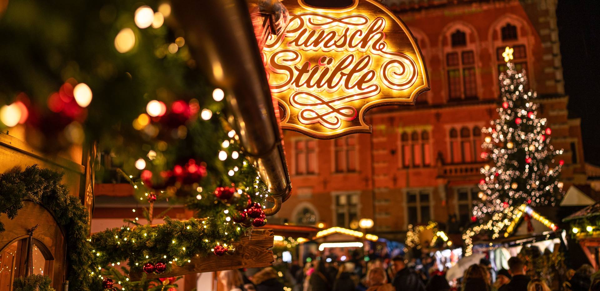 Punsch Stüble auf dem Oldenburger Weihnachtsmarkt mit Rathaus im Hintergrund.