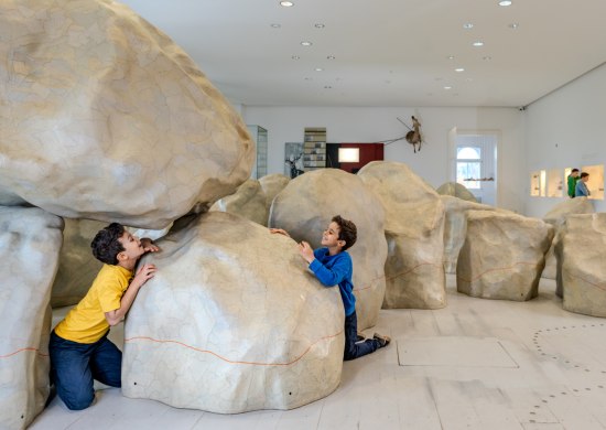 Zwei Kinder spielen im Landesmuseum Natur und Mensch Oldenburg im Modell eines Großsteingrabs. 